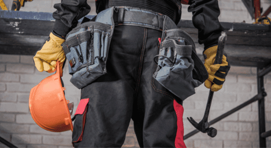 Worker from behind with utility belt, hard hat and hammer