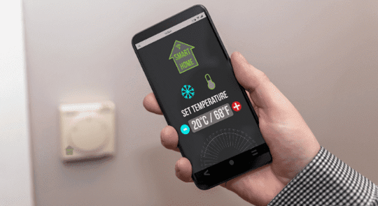 hand holding phone showing smart home thermostat